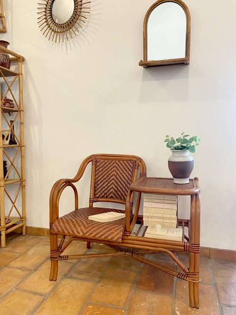 Une mise en scène de la boutique : fauteuil et console en rotin sous un miroir soleil